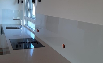 Küche mit Compac Quarzagglo Arbeitsplatten Moon und Glasrückwände RAL-Farbe 9001